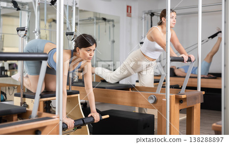 Focused woman performing set of pilates exercises on reformer in fitness studio. Healthy active lifestyle concept 138288897