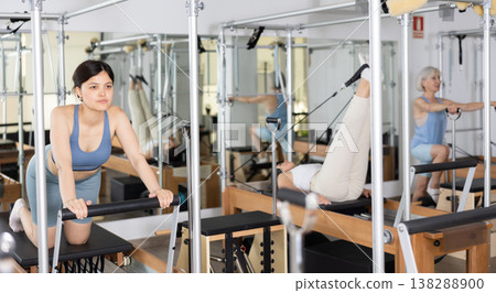 Young asian girl performing pilates exercises on reformer Young asian girl performing pilates exercises on reformer 138288900