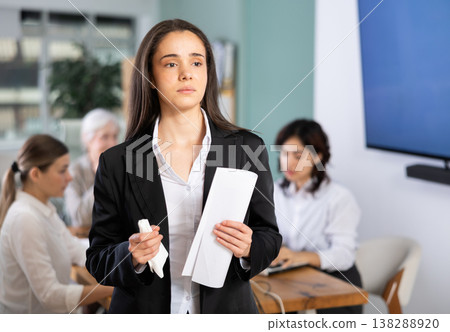 Sad young woman holding document in office Sad young woman holding document in office 138288920
