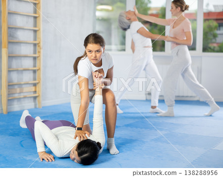 Young woman applying armlock to female opponent in simulated sparring during self-defense class 138288956