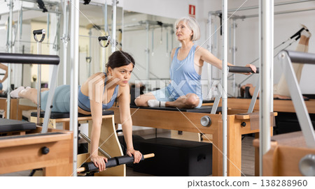 Focused woman performing set of pilates exercises on reformer in fitness studio. Healthy active lifestyle concept 138288960