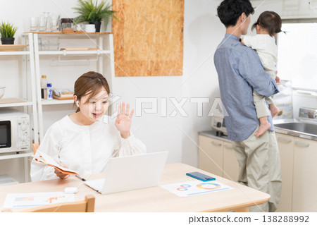 A wife works remotely while her husband babysits the children. A wife works remotely while her husband babysits the children. 138288992