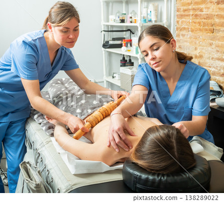 Two professional masseuses performing Maderotherapy for young woman Two professional masseuses performing Maderotherapy for young woman 138289022