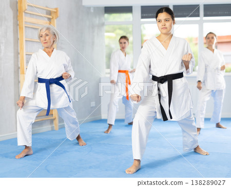 Young female karate sensei leading group of women during kata training Young female karate sensei leading group of women during kata training 138289027