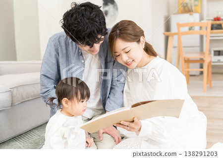 一對年輕夫婦給嬰兒讀圖畫書 138291203