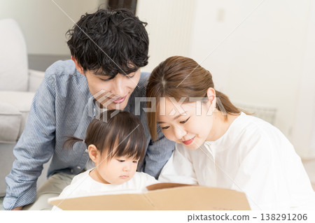 一對年輕夫婦給嬰兒讀圖畫書 138291206