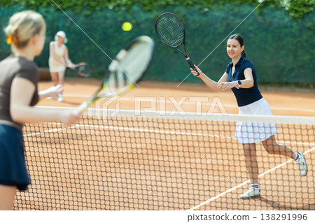 Adult woman playing doubles tennis on court 138291996