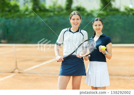 Two girls in sportswear against backdrop of outdoor tennis court Two girls in sportswear against backdrop of outdoor tennis court 138292002