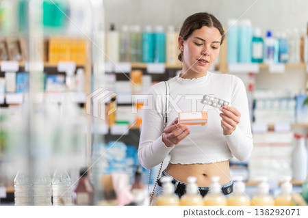 woman in summer clothes chooses a package of pallets in a pharmacy woman in summer clothes chooses a package of pallets in a pharmacy 138292071