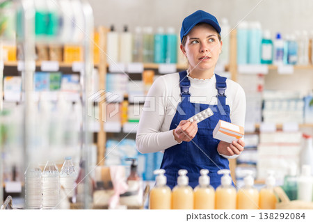 In sales area of pharmacy, builder woman examines packaging of tablet pill 138292084