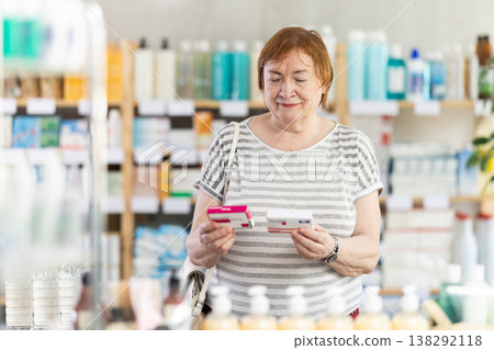 Mature woman in summer clothes buys paracetamol medicine at pharmacy 138292118