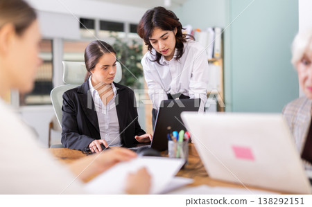 Young woman helping colleague work on laptop in office Young woman helping colleague work on laptop in office 138292151