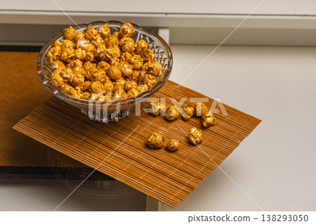Popcorn in a bowl on a brown mat with some pieces scattered nearby Popcorn in a bowl on a brown mat with some pieces scattered nearby 138293050