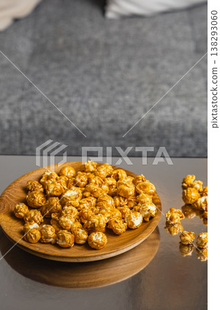 Caramel popcorn served on a wooden plate at a cozy indoor setting Caramel popcorn served on a wooden plate at a cozy indoor setting 138293060