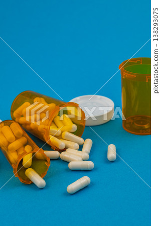 Pill bottles spilled on blue background with capsules scattered around Pill bottles spilled on blue background with capsules scattered around 138293075