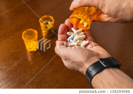 Holding capsules and pouring from a bottle in a home setting Holding capsules and pouring from a bottle in a home setting 138293098