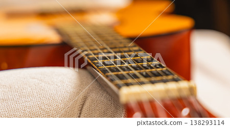 Close view of guitar resting on couch with focus on strings and body Close view of guitar resting on couch with focus on strings and body 138293114