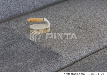 Cleaning a gray sofa with a brush on a soft surface for simple maintenance Cleaning a gray sofa with a brush on a soft surface for simple maintenance 138293121