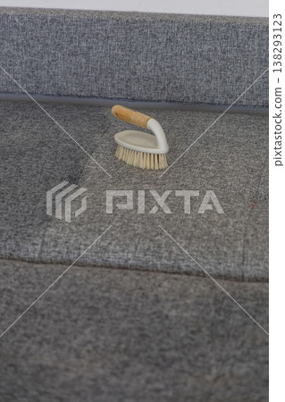 Dusting a gray fabric couch with a brush on a clean surface Dusting a gray fabric couch with a brush on a clean surface 138293123
