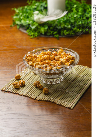 Bowl of popcorn sits on a bamboo mat next to some scattered kernels Bowl of popcorn sits on a bamboo mat next to some scattered kernels 138293129