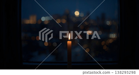 Single burning candle on a dark windowsill with a soft bokeh city skyline and glowing night lights in the background. 138293298