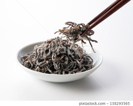 一張照片,畫面中鹽漬昆布盛放在小白碟子裡,用筷子夾著,背景是白色。 一張照片,畫面中鹽漬昆布盛放在小白碟子裡,用筷子夾著,背景是白色。 138293565