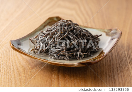 一張照片,照片中是一盤鹹海帶,盛放在陶瓷盤中,置於木桌上。 一張照片,照片中是一盤鹹海帶,盛放在陶瓷盤中,置於木桌上。 138293566