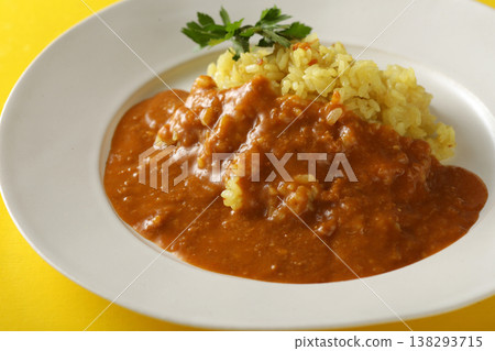 A close-up of chicken and beef curry with plenty of meat, served over saffron rice. 138293715