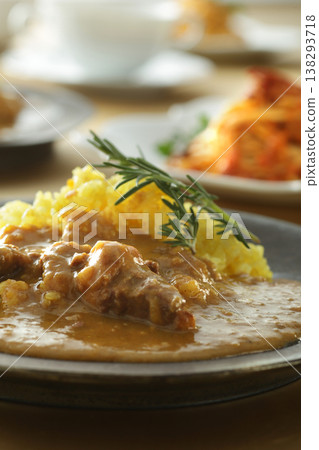 A close-up of chicken and beef curry with plenty of meat, served over saffron rice. 138293718
