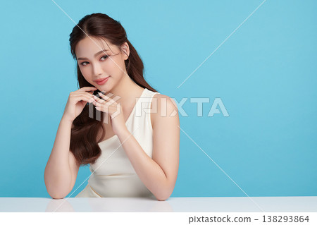 A beautiful young Asian woman with clean, fresh skin against a blue background. Skincare, facial treatment, cosmetology, beauty, and spa. An elegant portrait of an Asian woman. A beautiful young Asian woman with clean, fresh skin against a blue background. Skincare, facial treatment, cosmetology, beauty, and spa. An elegant portrait of an Asian woman. 138293864