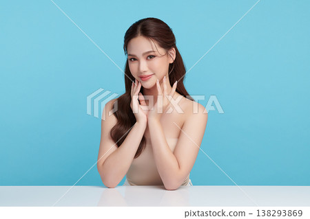 A beautiful young Asian woman with clean, fresh skin against a blue background. Skincare, facial treatment, cosmetology, beauty, and spa. An elegant portrait of an Asian woman. A beautiful young Asian woman with clean, fresh skin against a blue background. Skincare, facial treatment, cosmetology, beauty, and spa. An elegant portrait of an Asian woman. 138293869