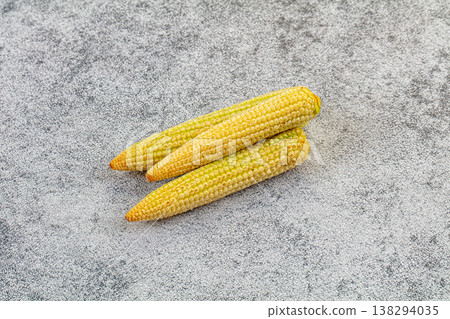 Pile of fresh raw baby corn on a textured background 138294035
