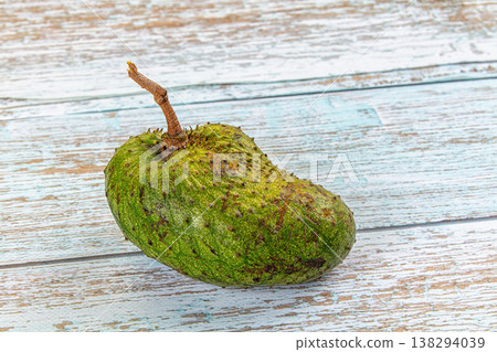One whole raw soursop fruit, or graviola, isolated on a textured background. One whole raw soursop fruit, or graviola, isolated on a textured background. 138294039