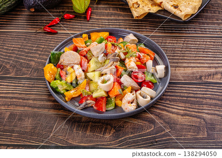 Fresh seafood and vegetable salad with shrimp, tuna and calamari next to flatbread and raw ingredients. 138294050