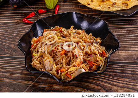 Stir-fried seafood noodles with shrimp and squid in a bowl on a wooden table. Stir-fried seafood noodles with shrimp and squid in a bowl on a wooden table. 138294051