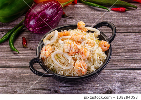 Shrimp and calamari rice with green onions in a white bowl on a rustic wooden table. Shrimp and calamari rice with green onions in a white bowl on a rustic wooden table. 138294058