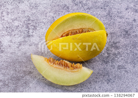 Fresh ripe yellow melon with a slice and visible seeds on a rustic background. 138294067