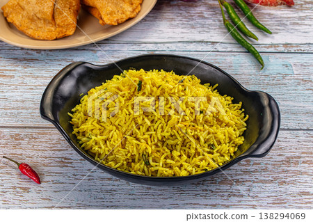Bowl of yellow basmati rice pilaf with herbs, served with appetizers on a rustic wooden table. 138294069