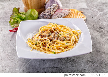 Spaghetti with mussels and herbs on a white plate with fresh seafood ingredients on a grey table Spaghetti with mussels and herbs on a white plate with fresh seafood ingredients on a grey table 138294113