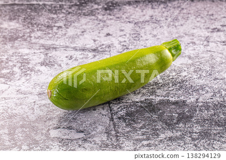 Single fresh green zucchini or courgette on a textured grey stone background. Single fresh green zucchini or courgette on a textured grey stone background. 138294129