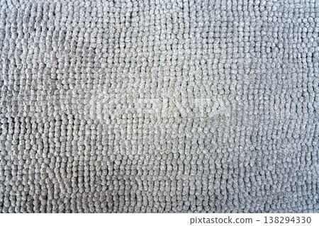 Top-down macro shot of a grey chenille microfiber rug texture. The image shows small soft fabric bumps in a grid pattern, suitable for interior design or home textile product themes. Top-down macro shot of a grey chenille microfiber rug texture. The image shows small soft fabric bumps in a grid pattern, suitable for interior design or home textile product themes. 138294330