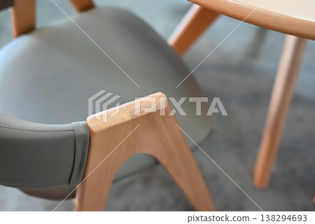 A wooden armchair with soft curves and a round dining table. 138294693