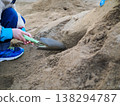 A scene of children playing in the sand and trying to dig a tunnel. 138294787