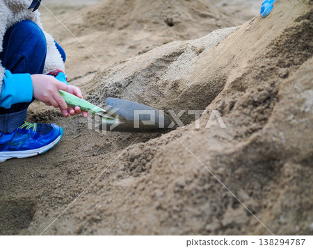 A scene of children playing in the sand and trying to dig a tunnel. A scene of children playing in the sand and trying to dig a tunnel. 138294787