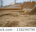 Image of a children's playground: A playground made of buckets, shovels, and wooden stakes placed in a sandbox. 138294790