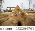 A large sandcastle and colorful cookie cutters left behind after playing in the park's sandbox. 138294791