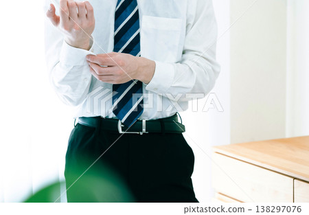 A businessman fastening the buttons on his sleeves. A businessman fastening the buttons on his sleeves. 138297076
