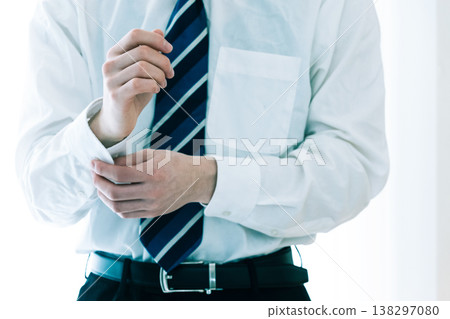 A businessman fastening the buttons on his sleeves. A businessman fastening the buttons on his sleeves. 138297080