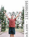 Happy Southeast Asian man celebrating victory with raised hands outdoors 138298095