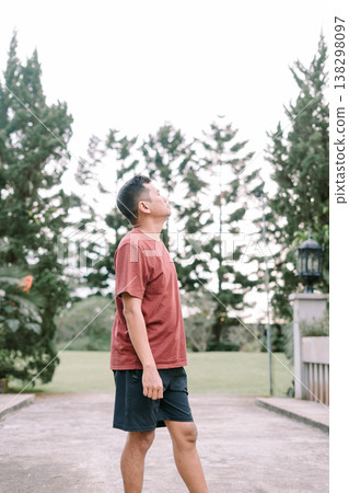 Southeast Asian man looking sideways and up in relaxed outdoor setting Southeast Asian man looking sideways and up in relaxed outdoor setting 138298097